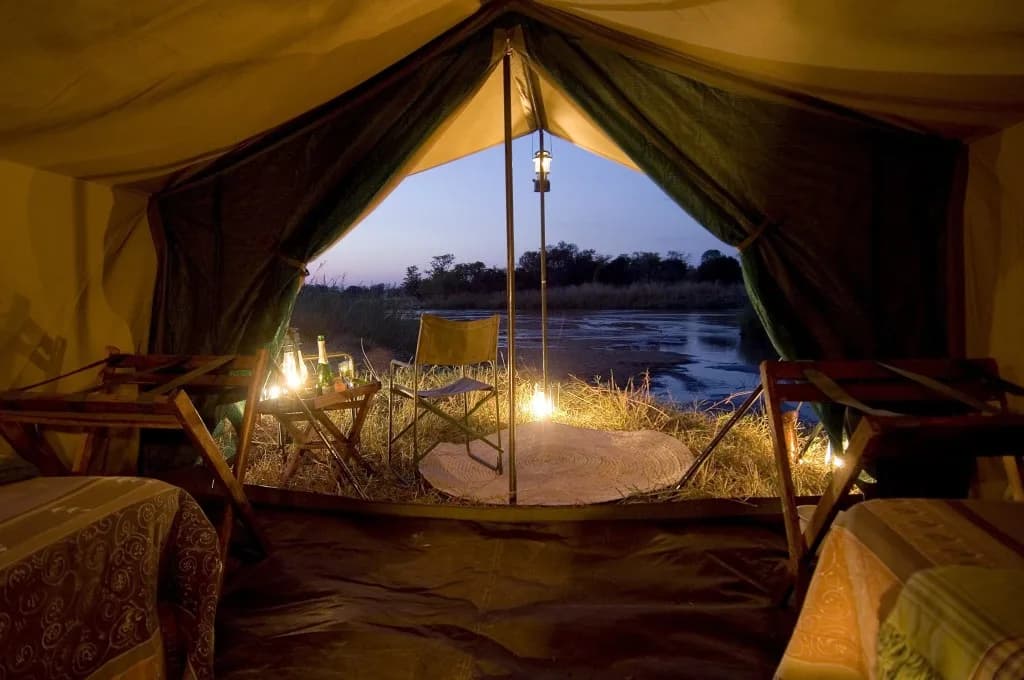 A camp tent open to dusk water — Moh Camping mood