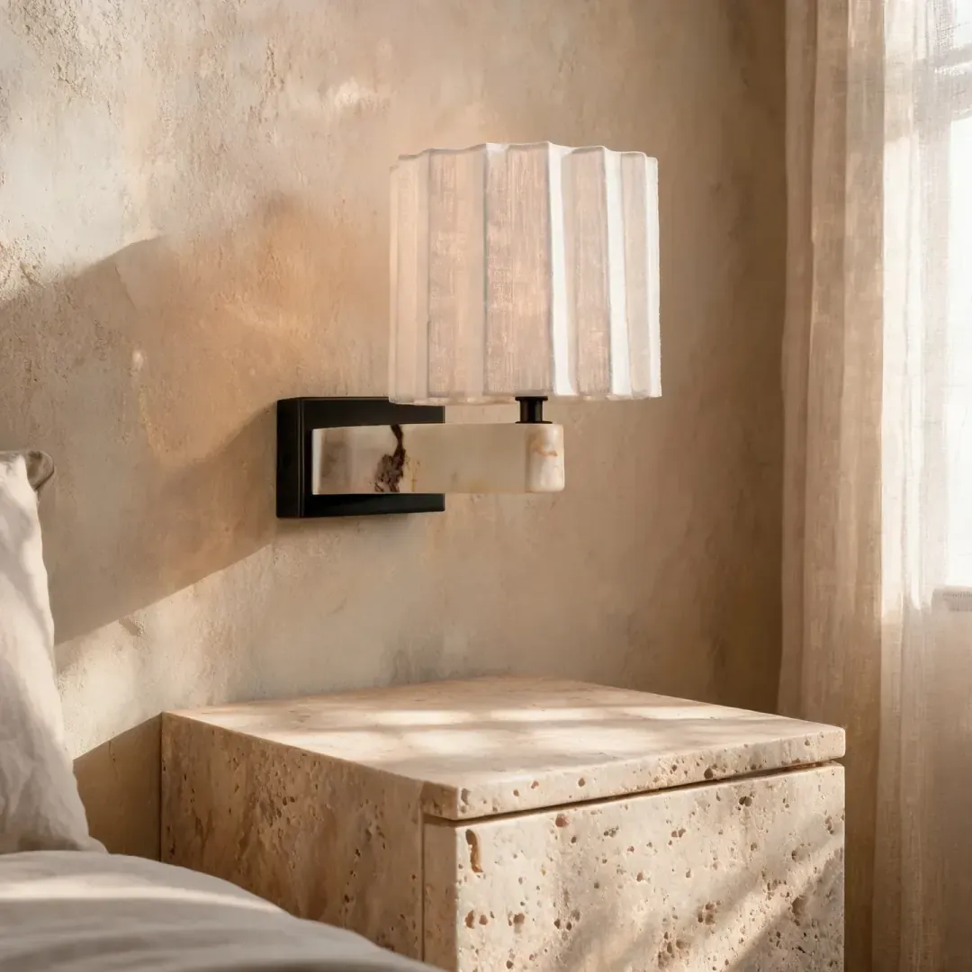 Stone bedside and a linen-shade lamp in morning light