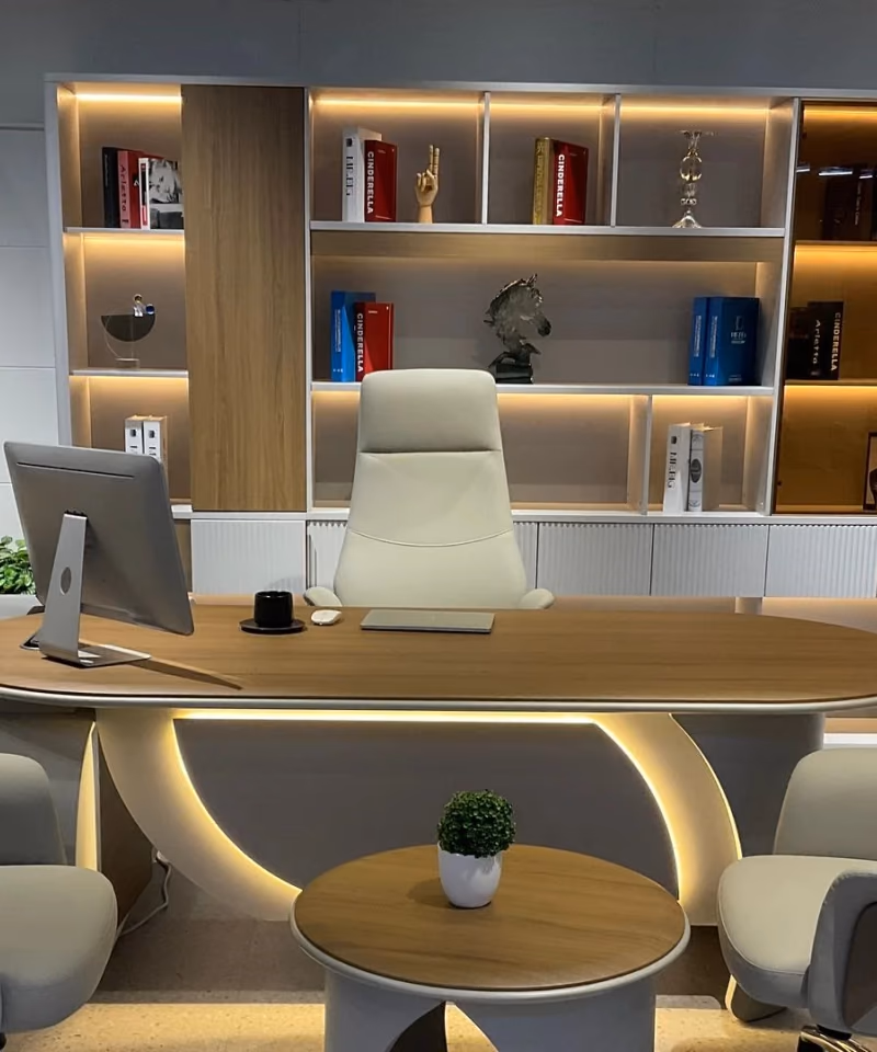A pale wood desk and cream chairs before lit shelves — Abi Library mood