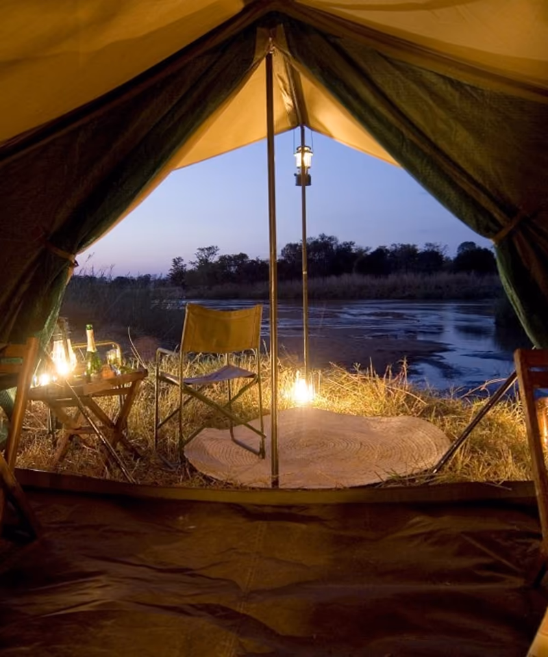 A camp tent open to dusk water — Moh Camping mood